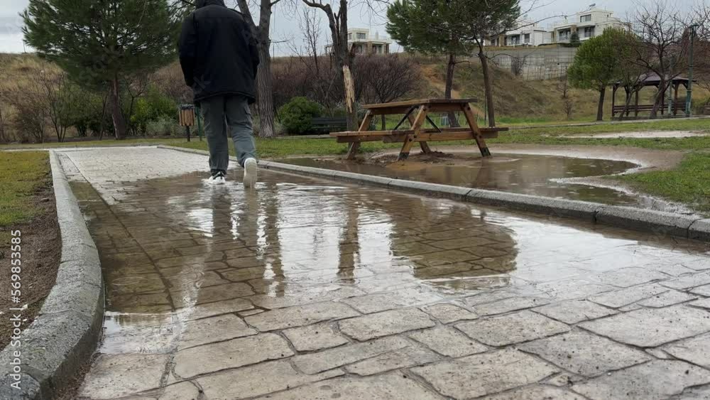 Man Walk In The Park Wearing Hoodie, Water Reflections Rainy Gloomy Day Man Walk In The Park Wearing Hoodie, Water Reflections Rainy Gloomy Day