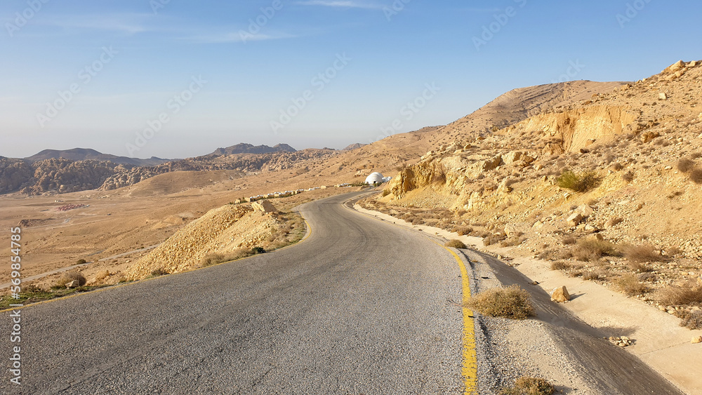 Long, winding and quiet highway road to bubble tent accommodation in Middle Eastern scenic desert landscape of Jordan