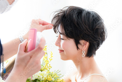 ヘアメイクをされるミモザの花束を抱える可愛らしい女性 photo