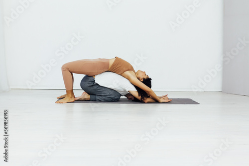 acrobatics woman stretches her back on a man training yoga classes in the gym photo