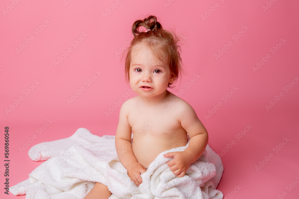 baby girl in a diaper wrapped in a towel sitting on a pink background, bathing concept baby girl in a diaper wrapped in a towel sitting on a pink background, bathing concept