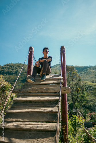 Chico sentado bajo el sol al final de una escalera al aire libre