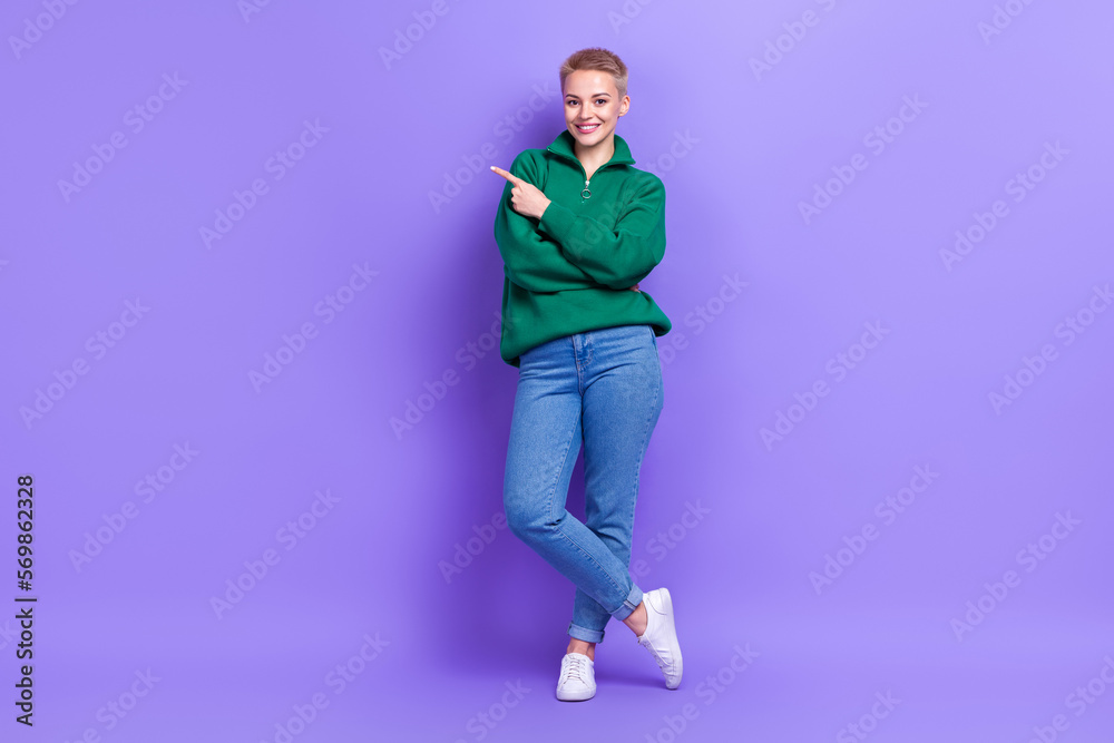 Full length photo of confident adorable lady wear green sweater pointing empty space isolated violet color background Full length photo of confident adorable lady wear green sweater pointing empty space isolated violet color background