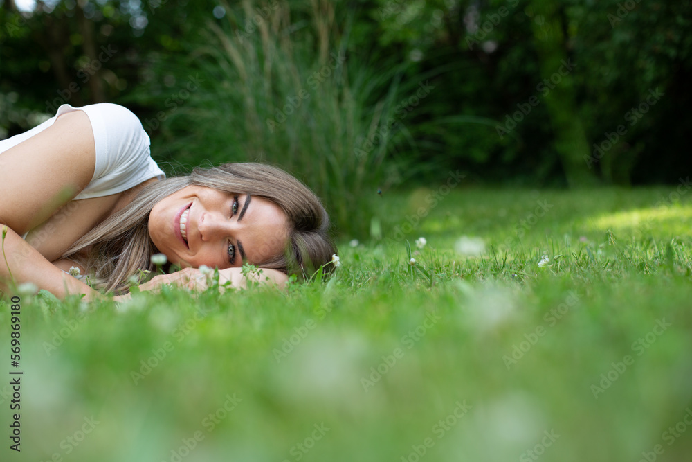 beautiful, young, blond woman lies in the garden in green grass and relaxes, dreams beautiful, young, blond woman lies in the garden in green grass and relaxes, dreams