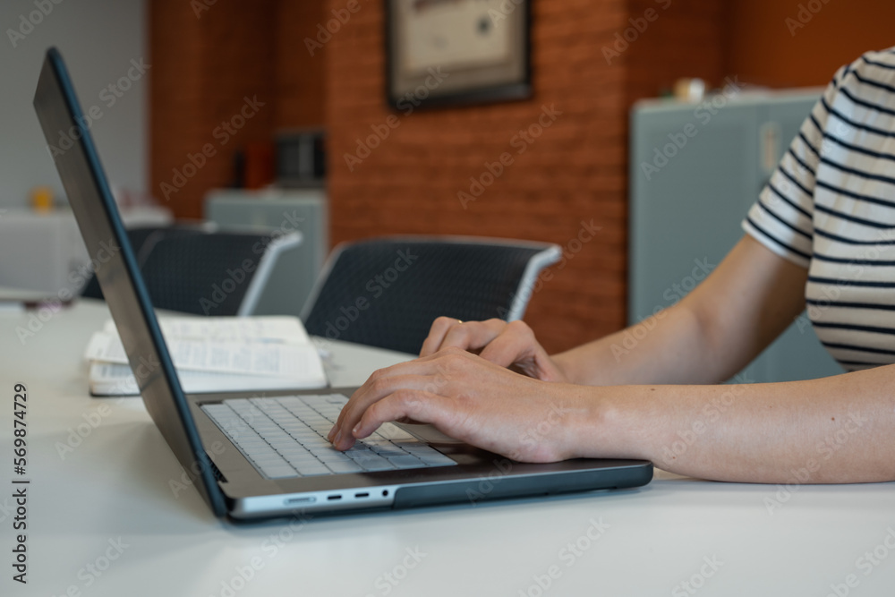 Fototapeta premium Pregnant woman sitting at desk with laptop in office. Real person in real situation.