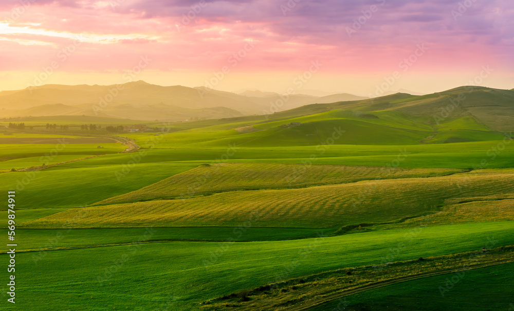 beautiful green valley with green fields with green spring grass with nive hills and mountains and scrnic colorful cloudy sunset on background of landscape