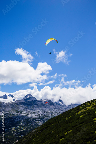 Paraglider flying over mountain peaks on a sunny day