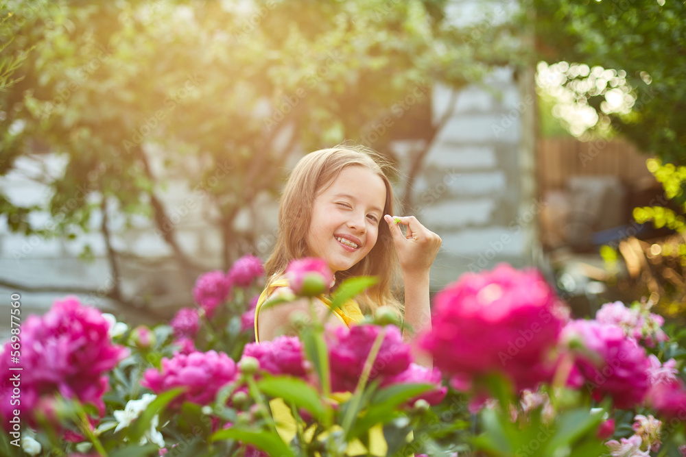 Happy little girl with braces in the garden in bushes of peonies Happy little girl with braces in the garden in bushes of peonies