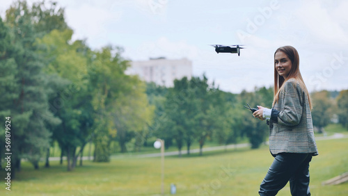 A cute girl controls a drone in the park.