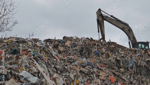 An excavator working at a landfill near the city.