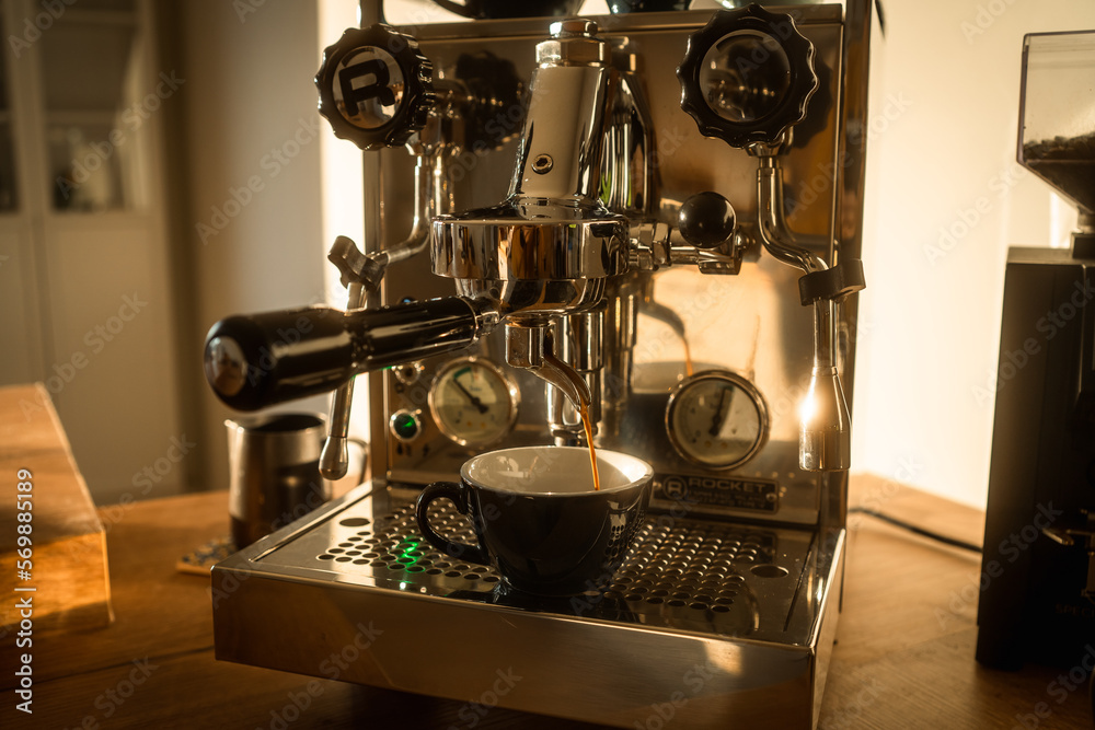 Barista pouring freshly brewed espresso in the morning sun at home with coffee maker machine