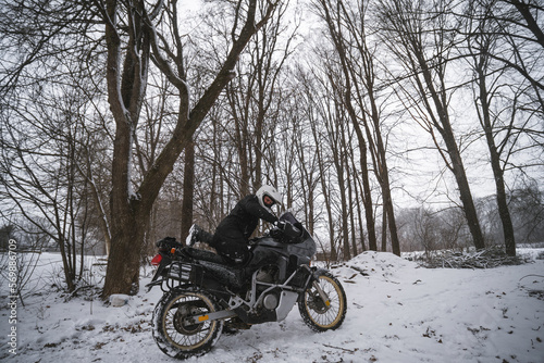 Motorcyclists enjoy extreme winter riding on a motorcycle, snowy forest, snowfall. The concept of transport and clothing for the cold season. Stupid ideas of grown men.