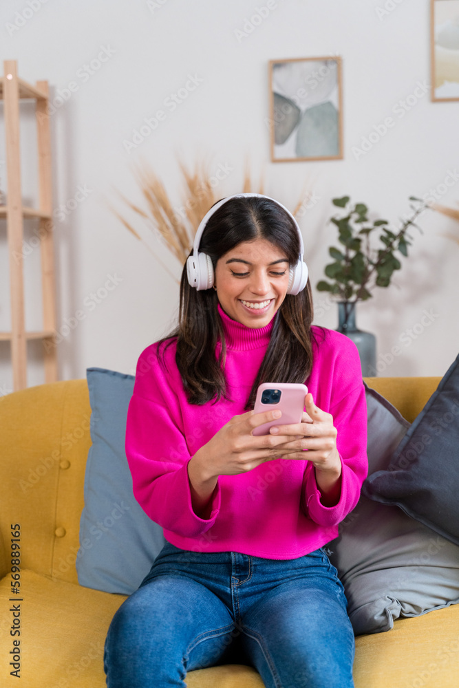 Obraz premium Cheerful woman in headphones using smartphone