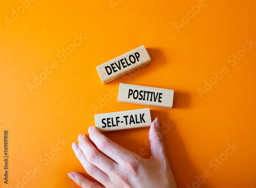 Develop positive self-talk symbol. Concept words Develop positive self-talk on wooden blocks. Businessman hand. Beautiful orange background. Business and Develop positive self-talk concept. Copy space