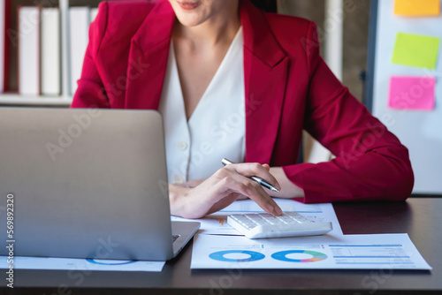 Marketing, Finance, Accounting, Planning, Portrait of a female accountant using a calculator and laptop to calculate balance using graphs for customers.