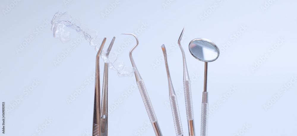 Dental tools and model of teeth on a blue background. Dental care concept. Invisible braces Dental tools and model of teeth on a blue background. Dental care concept. Invisible braces