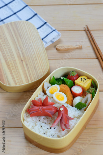 a cute delicious looking bento consists of steamed rice, sausage, boiled egg, broccoli, omelet, imitation crab meat and fresh strawberry  