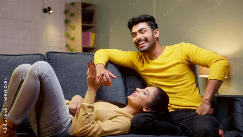 Girl lying on boyfriend lap while talking eachother on at home - concept of family time, romantic evening and embracing.