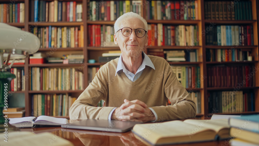 Inspired mature writer sitting in a library, completing last chapter of his new book Inspired mature writer sitting in a library, completing last chapter of his new book