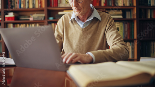 Senior man working on laptop, writing an article, doing research, freelance job