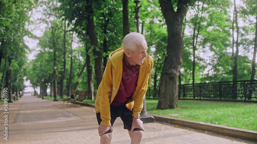 Senior man taking a break to catch his breath after running in morning park, workout