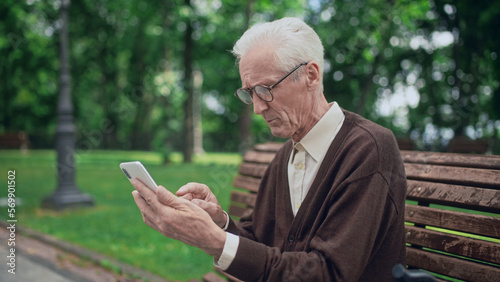 Senior man learning how to type on modern sensor smartphone, texting with relatives