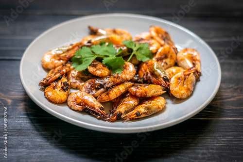 fried shrimp with soy sauce, garlic in gray plate on wooden table Seafood Traditional thai food