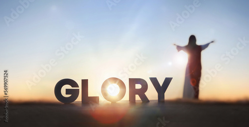 Christian praying with open arms toward the sky, giving praise and glory to God and the letter GLORY shining in the bright sunlight
 photo