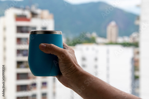 hand holding a mug of water with a view on the city background