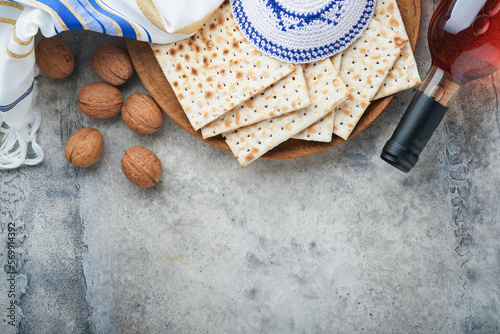 Passover celebration concept. Matzah, red kosher and walnut. Traditional ritual Jewish bread matzah, kippah and tallit on old concrete background. Passover food. Pesach Jewish holiday. photo