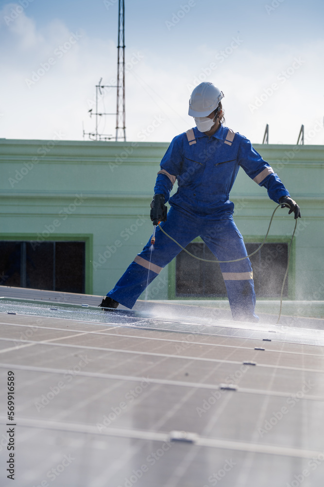 Obraz premium Technician using high pressure water to clean the solar panels that are dirty with dust and birds' droppings to improve the efficiency of solar energy storage.