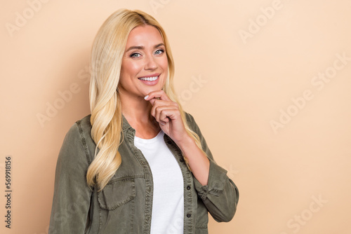 Photo of smart clever lady dressed green shirt arm chin empty space isolated beige color background