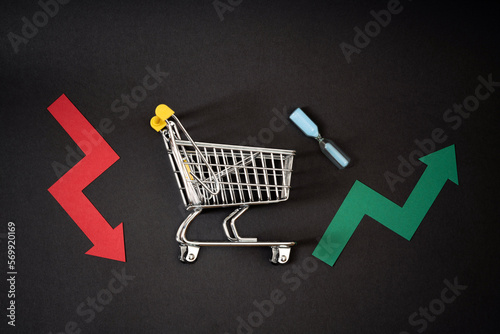 Indecision of costumer activity in the market. Shopping sales growth or decline. Shopping cart with up and down arrows on black background