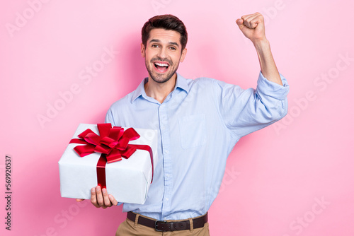 Photo of overjoyed man raise hand yeliling horray get new year presentisolated on pink color background photo