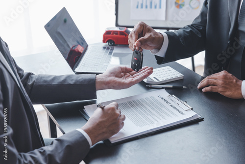 Obraz na plátně Concept of Car insurance or rental, salesman is making deal with buyer and giving key to him after sign sell contract or rental agreement