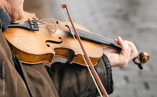 Old poor man playing the violin on the street, close up, street musician, copy space.