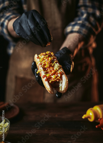 Hot dog with corn. A guy in an apron and gloves adds corn to a hot dog. Classic fast food