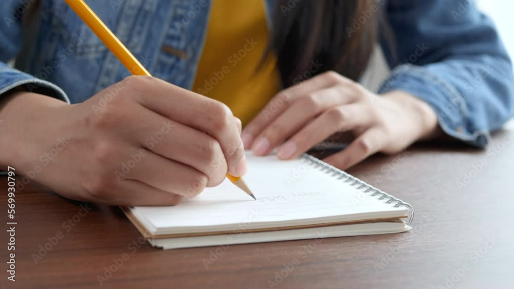 4K: cropped short, Hands of Young woman holding pen making notes in diary, close up view. 4K: cropped short, Hands of Young woman holding pen making notes in diary, close up view.
