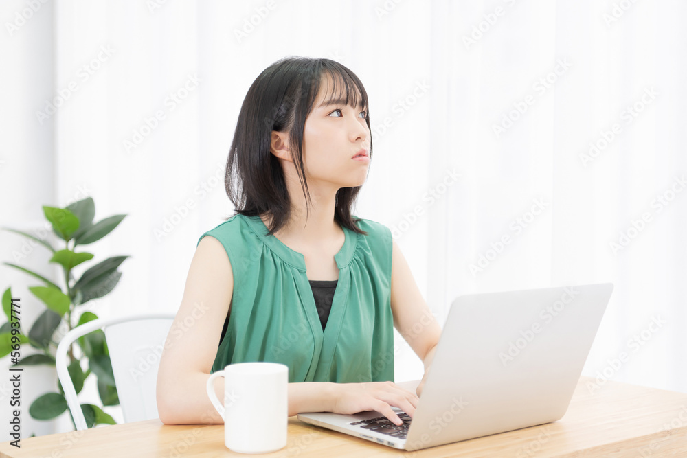 パソコンを使いながら外を見上げる若い女性 パソコンを使いながら外を見上げる若い女性