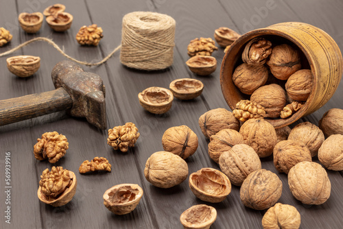 Walnuts are scattered from a wooden bowl on table.