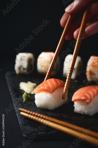 Crop person eating sushi with chopsticks