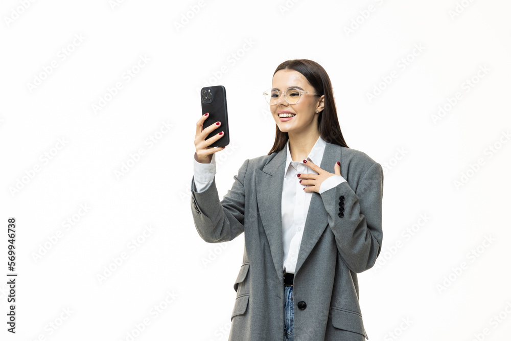 Happy business woman isolated over white wall backgound looking aside talking by phone waving to friends. Happy business woman isolated over white wall backgound looking aside talking by phone waving to friends.