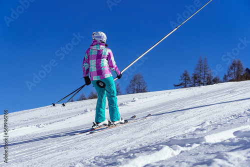 A young girl skier, climbs the slope at a ski resort, using a butt lift or ski lift. French Alps. photo