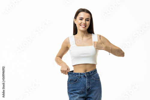 beautiful slim girl in big jeans thumbs up on white background