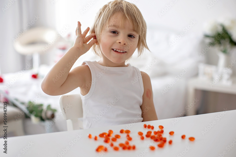 Cute little child, toddler boy, eating alfa omega 3 child suplement vitamin pills at home Cute little child, toddler boy, eating alfa omega 3 child suplement vitamin pills at home