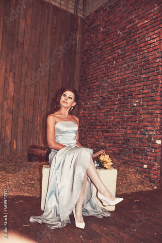 Wedding photos of the bride in a long, tight dress, with a bouquet of yellow orchids, with black arrows in her eyes, and curly red hair. Festive mood. A beautiful young girl is getting married.