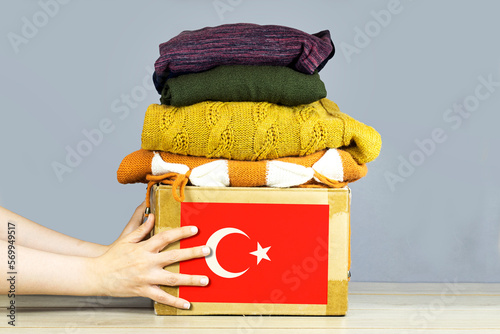 closeup woman hands holding carton box with used clothes for donation and turkey flag Earthquake, catastrophe volunteering photo