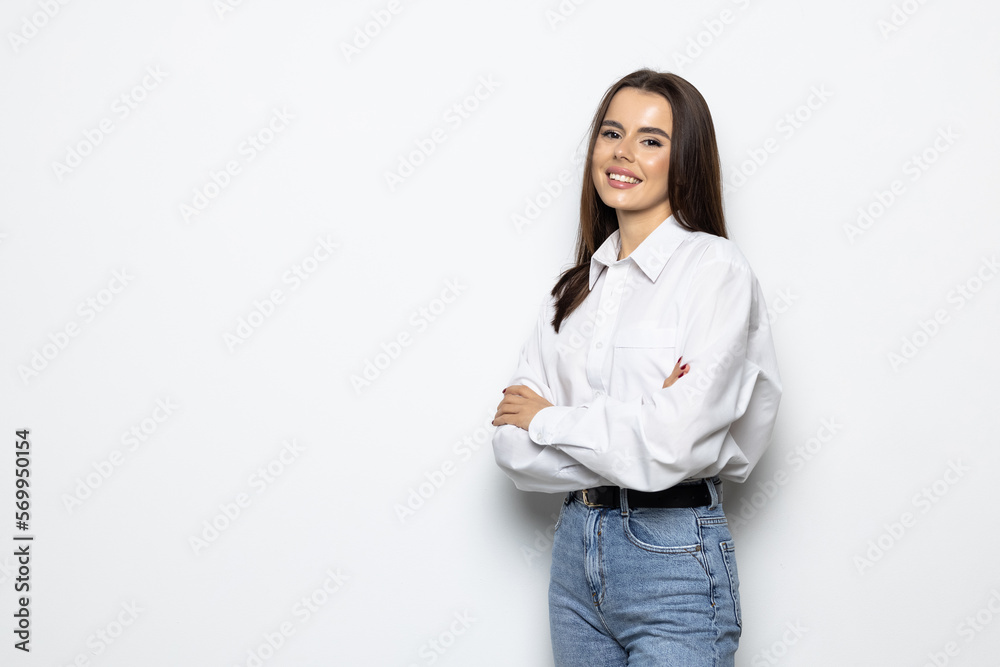 Smiling brunette woman posing with crossed arms and looking at the camera over white background Smiling brunette woman posing with crossed arms and looking at the camera over white background