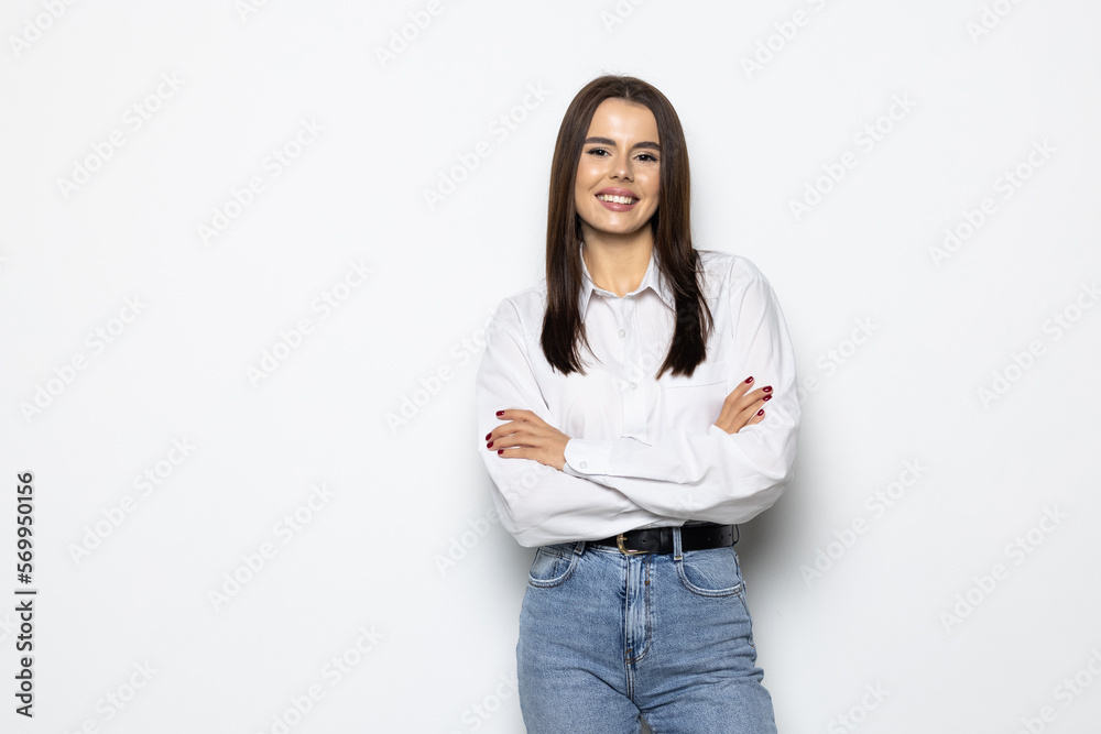 Smiling brunette woman posing with crossed arms and looking at the camera over white background Smiling brunette woman posing with crossed arms and looking at the camera over white background