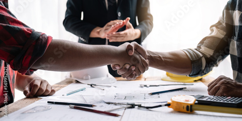 Shaking hands, Blueprints architects and building engineers talking meeting and planning will chronicle the design and technical aspects of a new house construction, renovation remodeling.